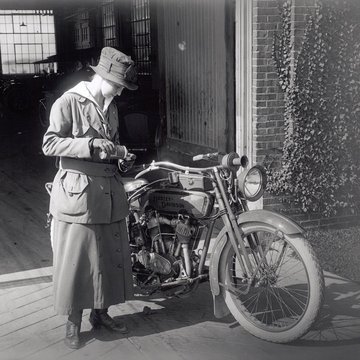 donna accanto a una moto nei primi del 1900