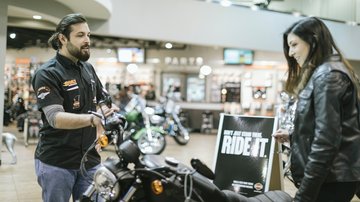 empleado de un concesionario ayudando a un cliente en la tienda de motocicletas