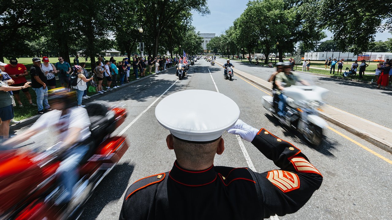 soldier salutes motorcycle riders as they drive by