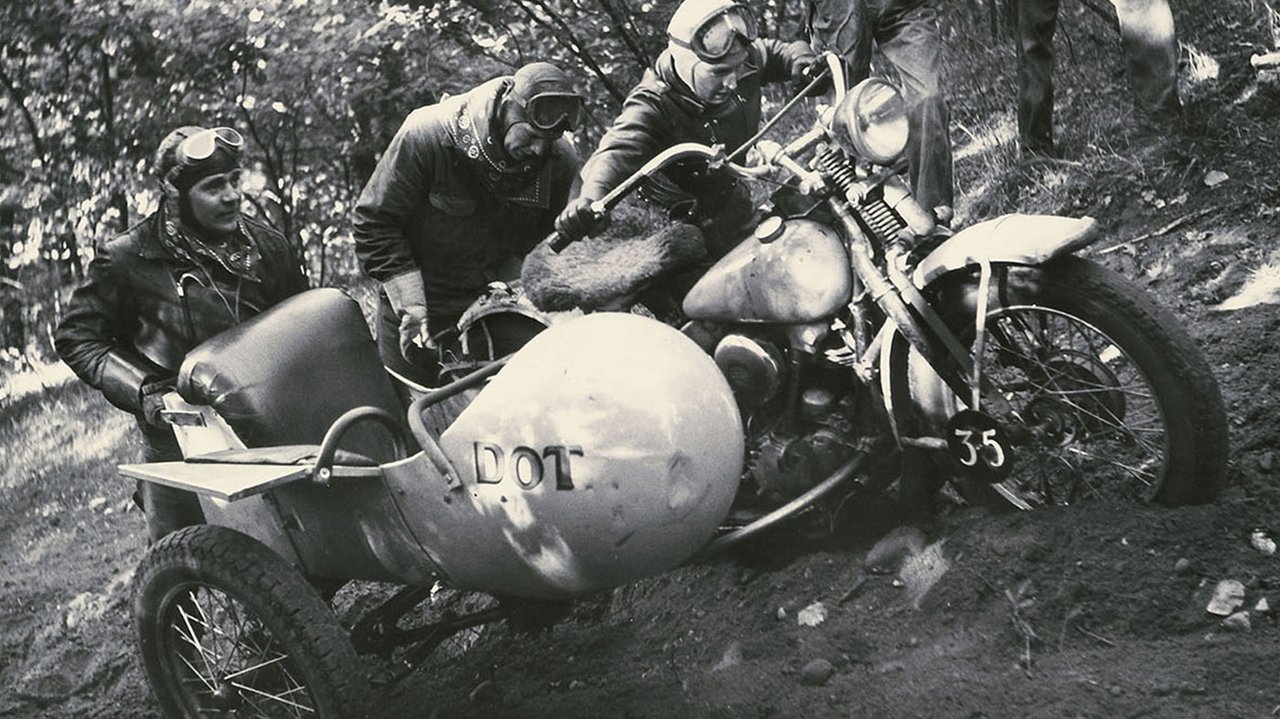 Arkivbillede af kørere, der skubber en motorcykel op af en grøft