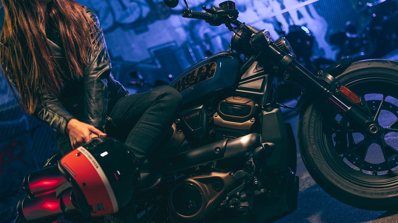 Cliché d’une femme assise sur une motocyclette Sportster S avec son casque H-D à la main